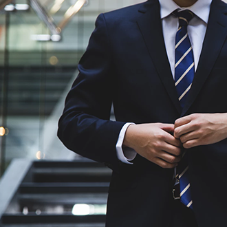 Man in suit adjusts cuff, symbolizing professionalism at Austria Business Center, Dubai.