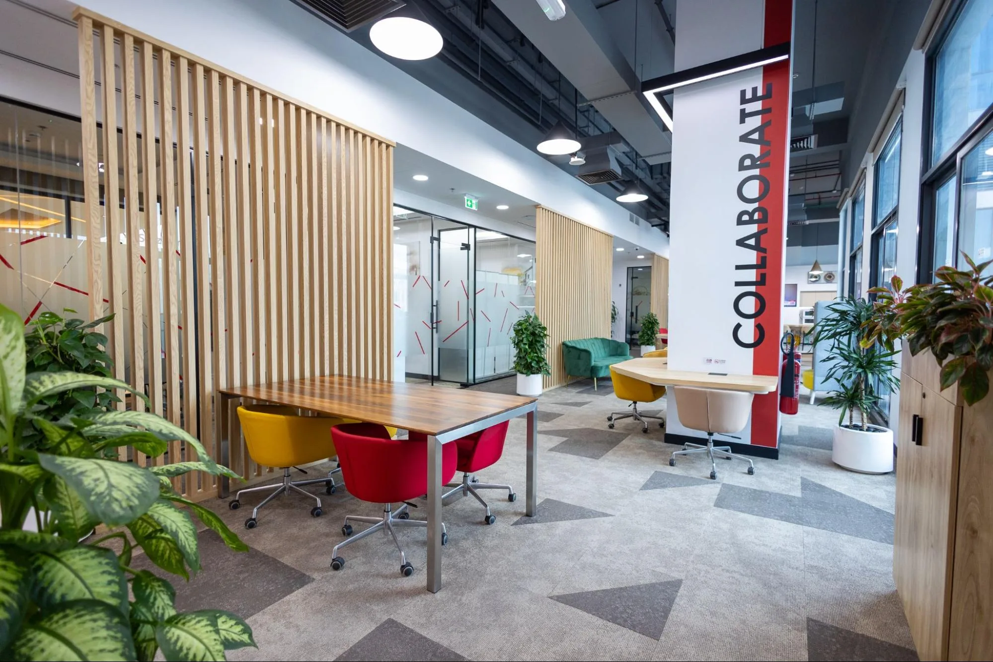 A modern, open-plan serviced office in Austria Business Center featuring a collaboration banner and a meeting table. 