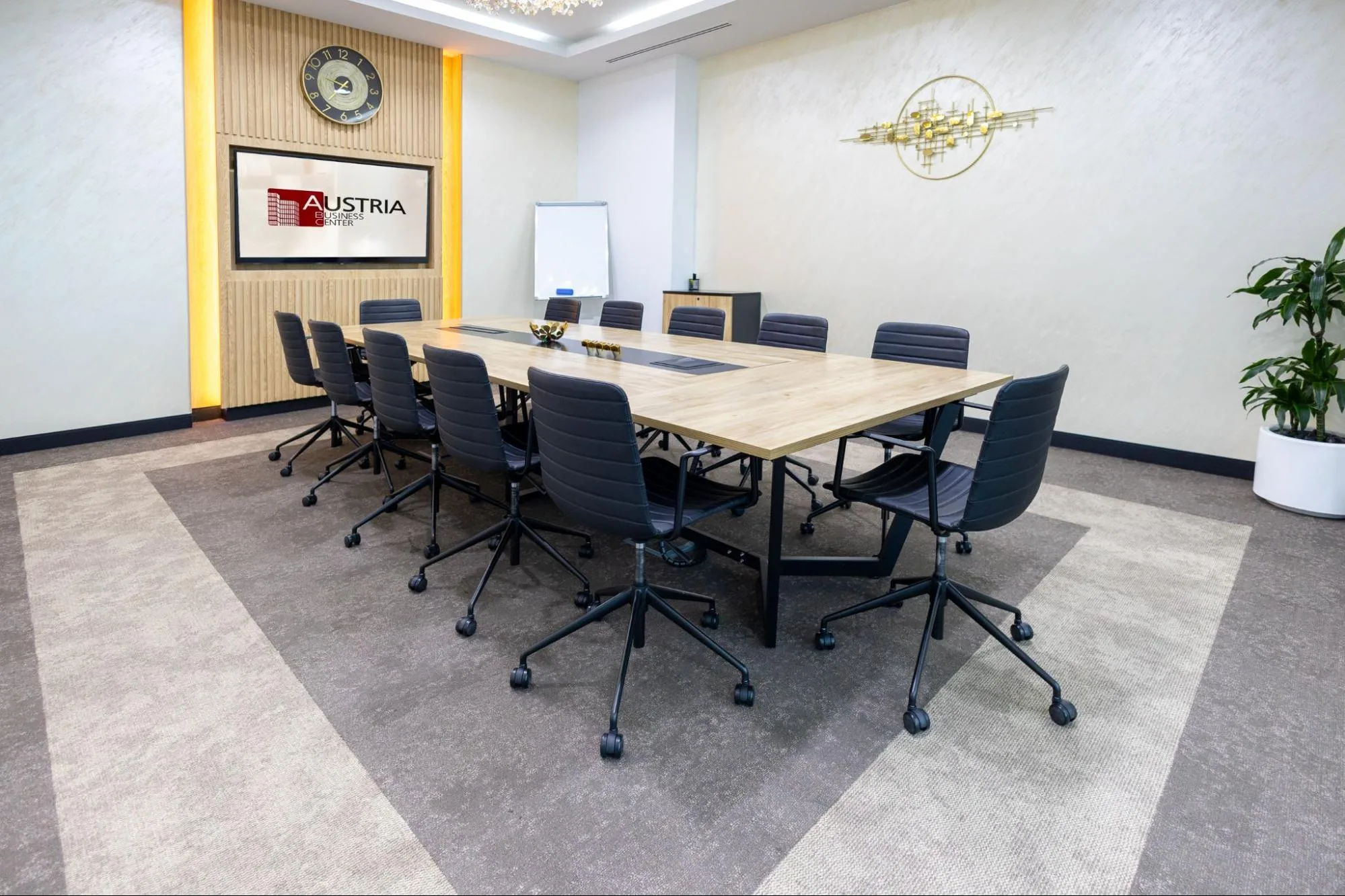 Al Hudaiba Mall Austria Business Center conference room with wooden table, black chairs, TV screen, and decorative walls.