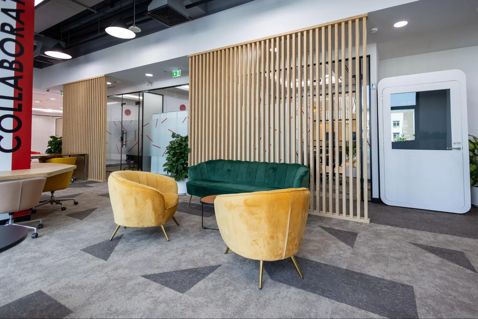 A modern, colorful serviced office in Austria Business Center with a green sofa, yellow armchairs, and a banner.
