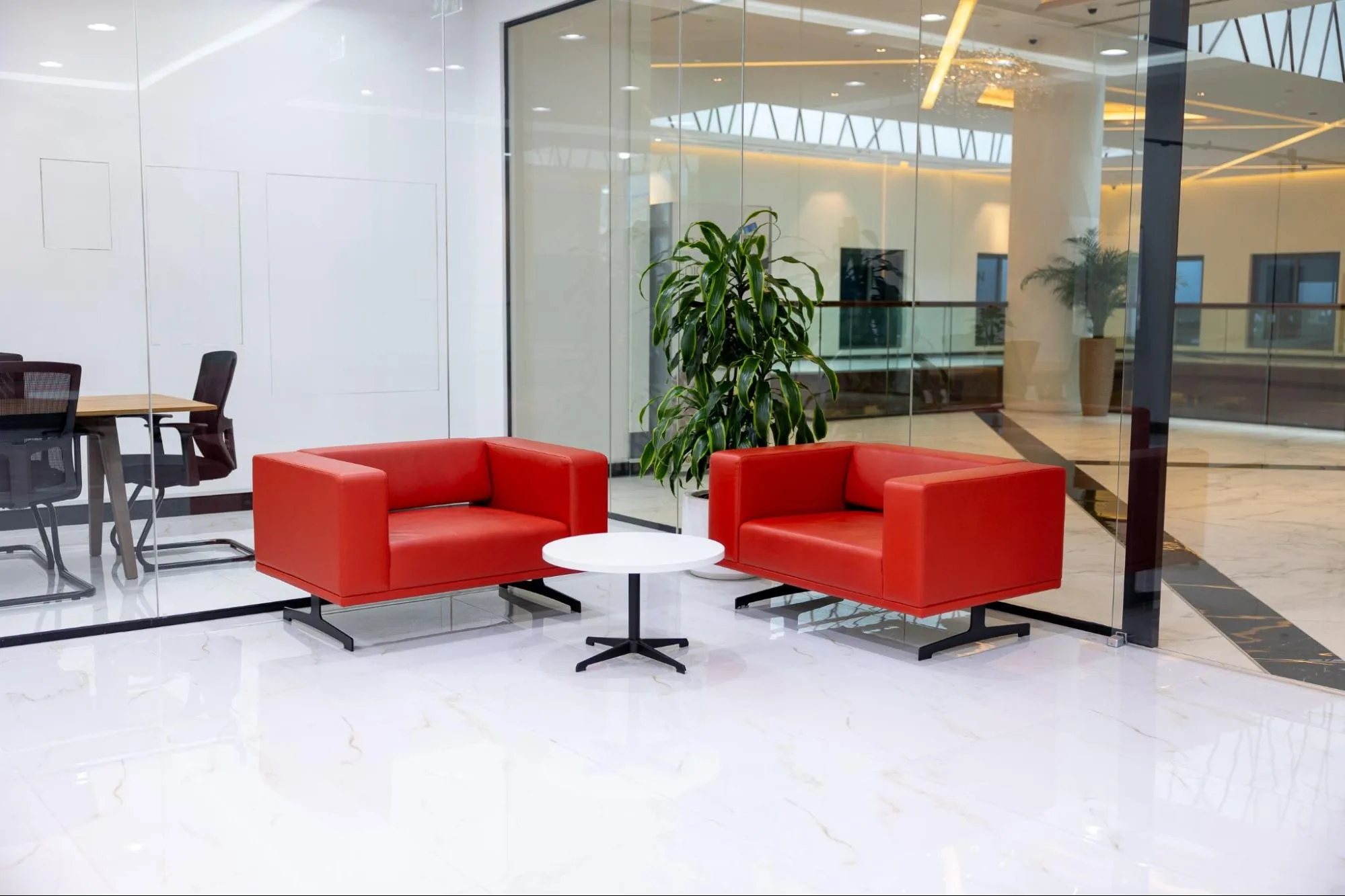 A modern virtual office in Dubai lobby with two red armchairs and a small white table.